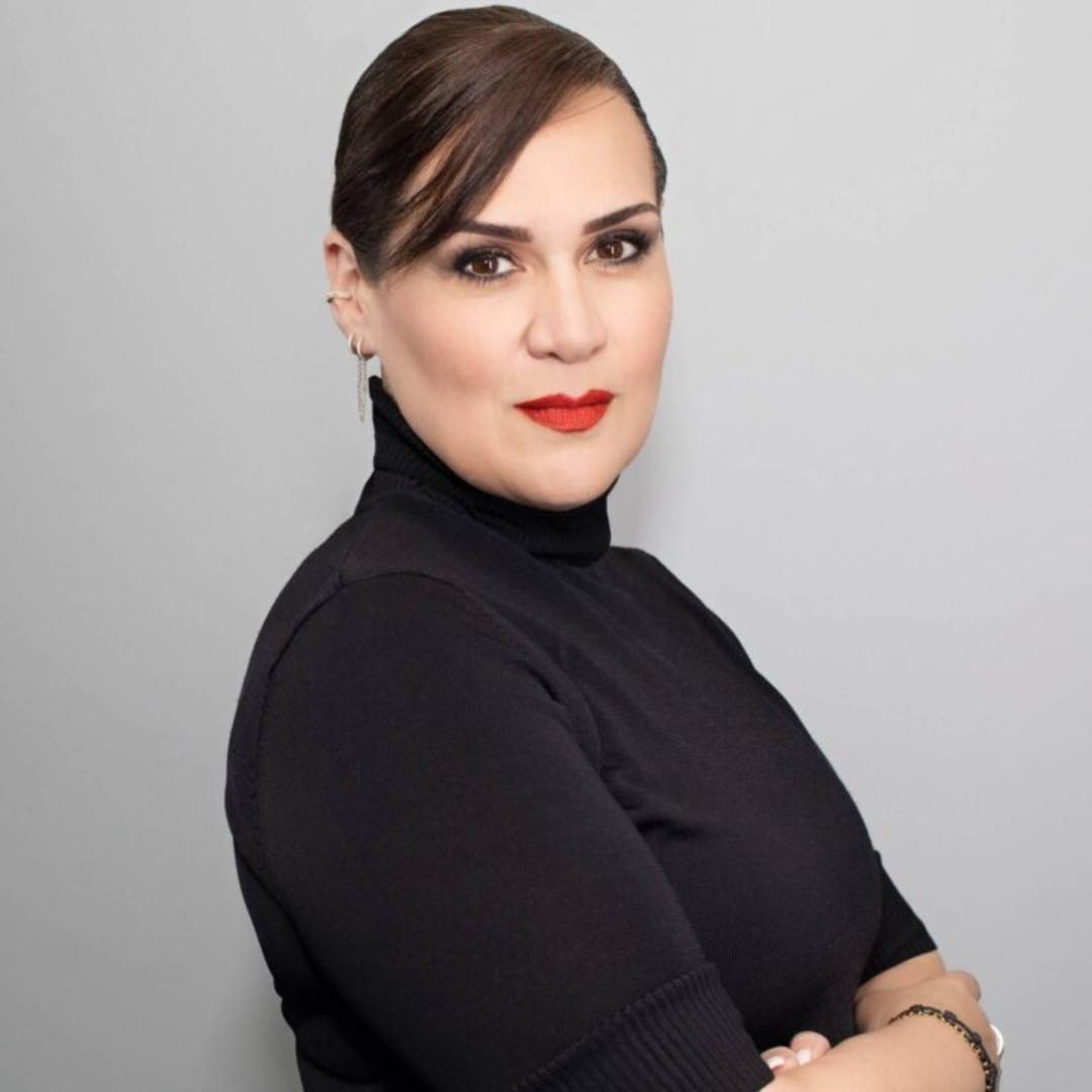 A woman in black shirt standing next to wall.