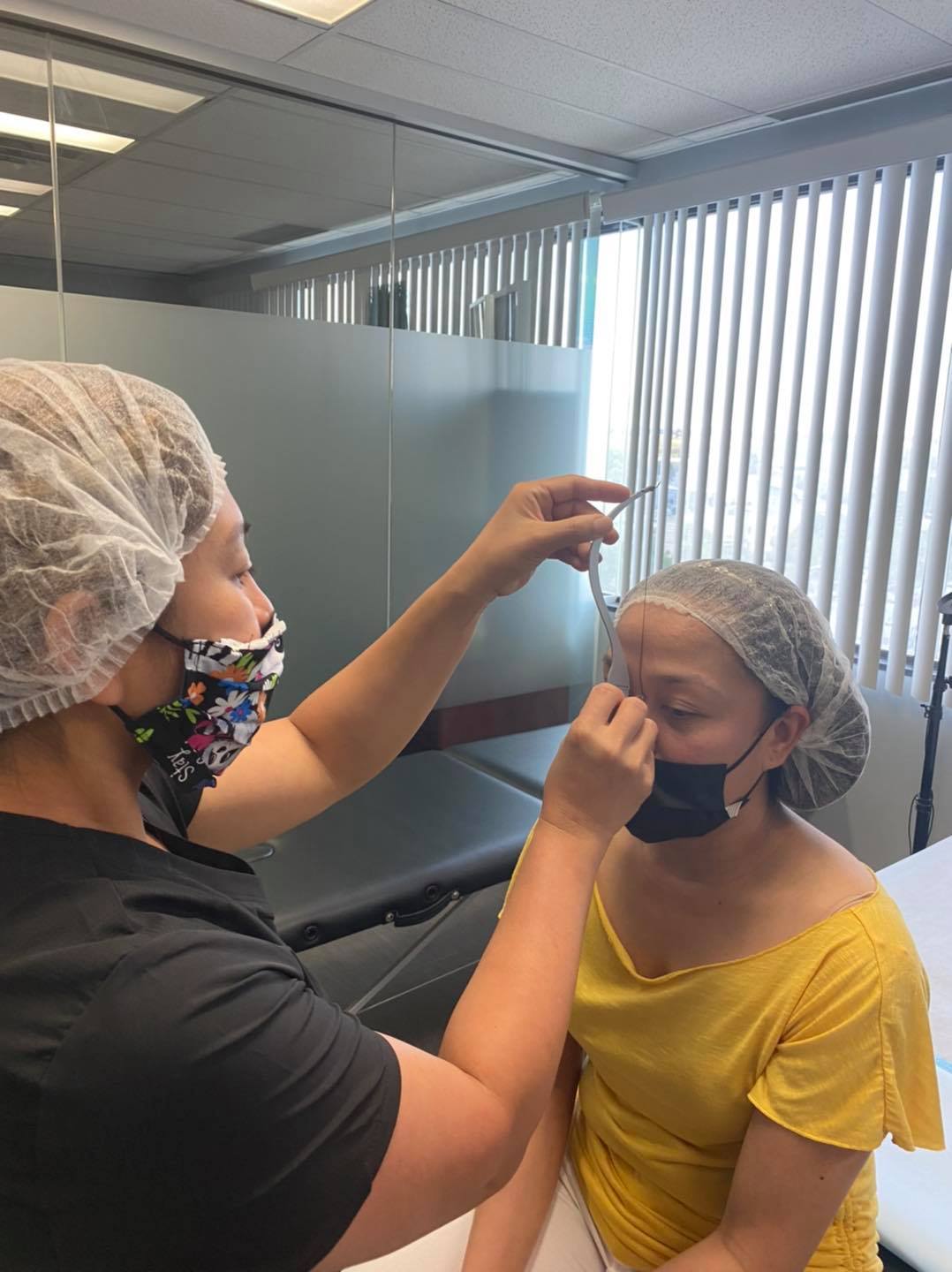 A woman in surgical mask is getting her face painted.