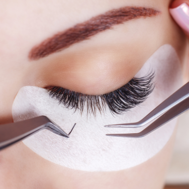 A woman is holding some scissors and a pair of eyelashes.