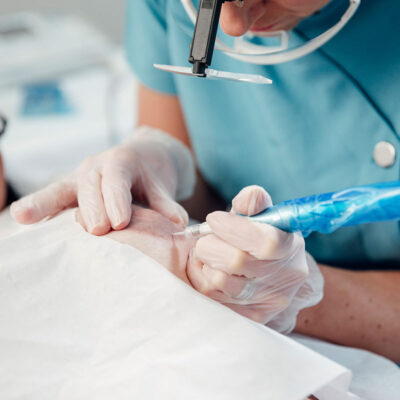 A person in blue shirt and white gloves working on paper.