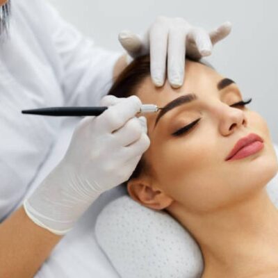 A woman getting her eyebrows tattooed by an esthetician.